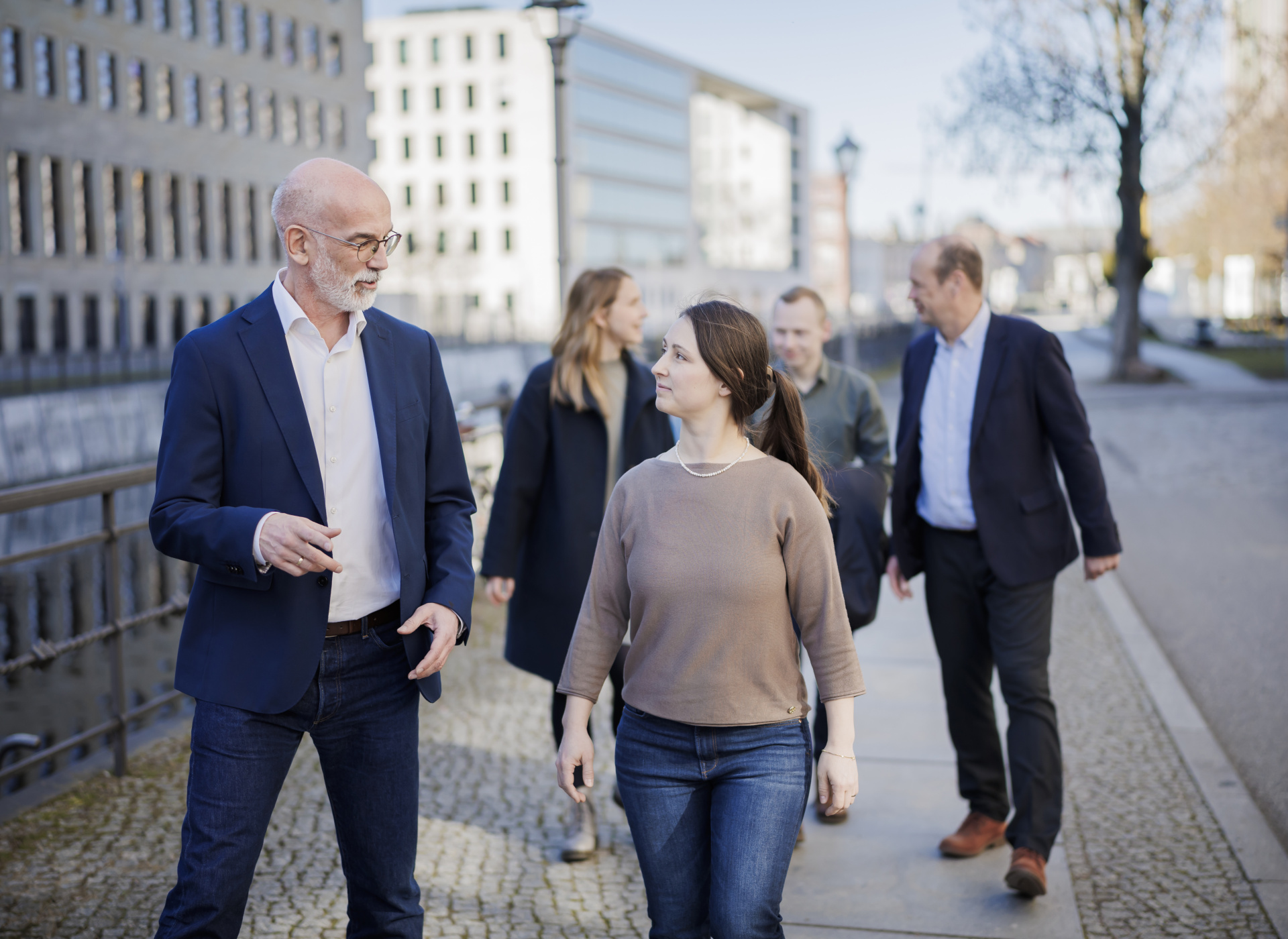 Gruppe von fünf Personen läuft über den Gehweg und unterhält sich.