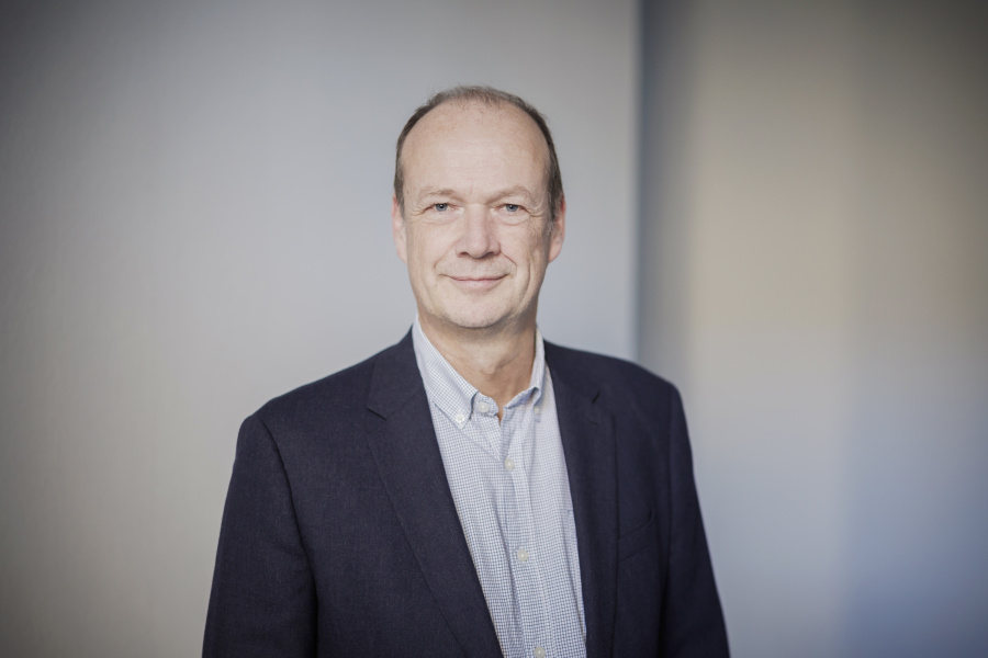 Männlich gelesene Person mit kurzen braunen Haaren blickt in die Kamera.