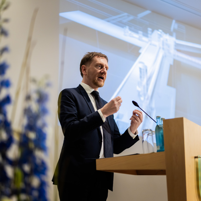 Männlich gelesene Person steht an einem Rednerpult.