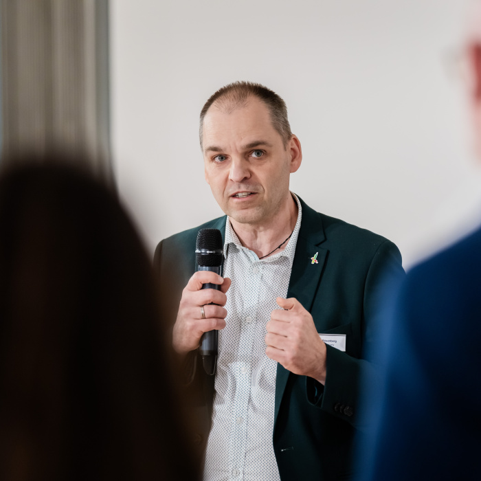 Männlich gelesene Person spricht in ein Mikrofon.