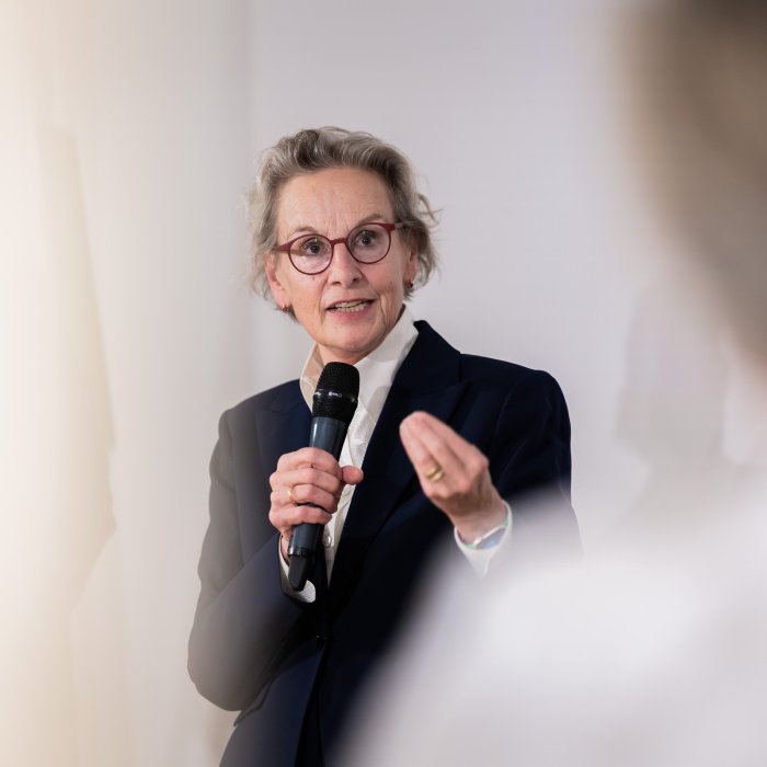 Weiblich gelesene Person spricht in ein Mikrofon.